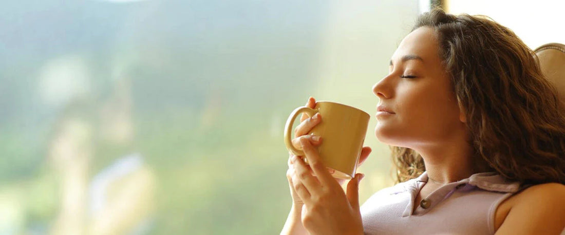 Junge Frau entspannt am Fenster und genießt entkoffeinierten Kaffee.