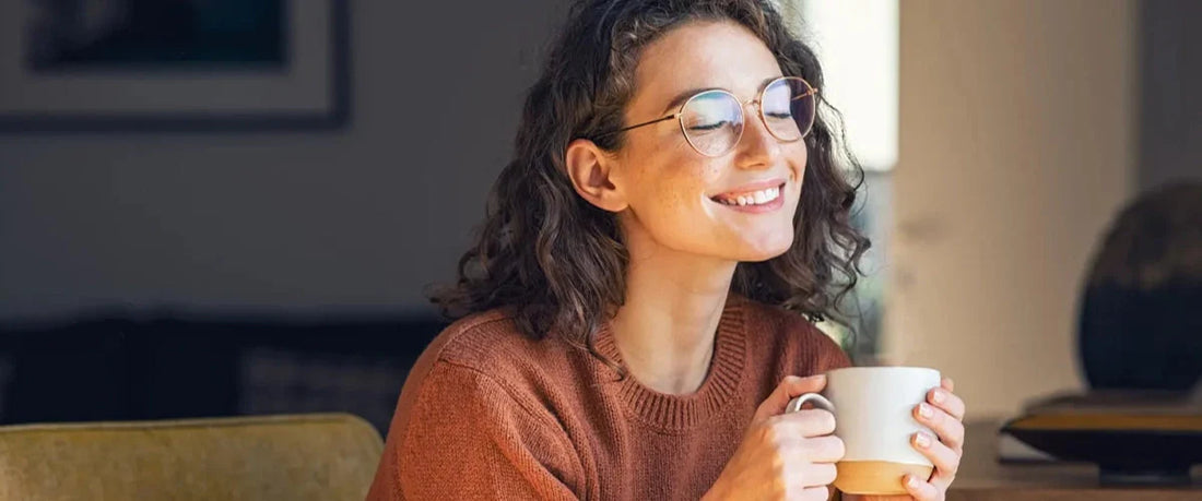 Junge Frau schaut zufrieden und hält eine Tasse Kaffee – Genuss und Gesundheit vereint.