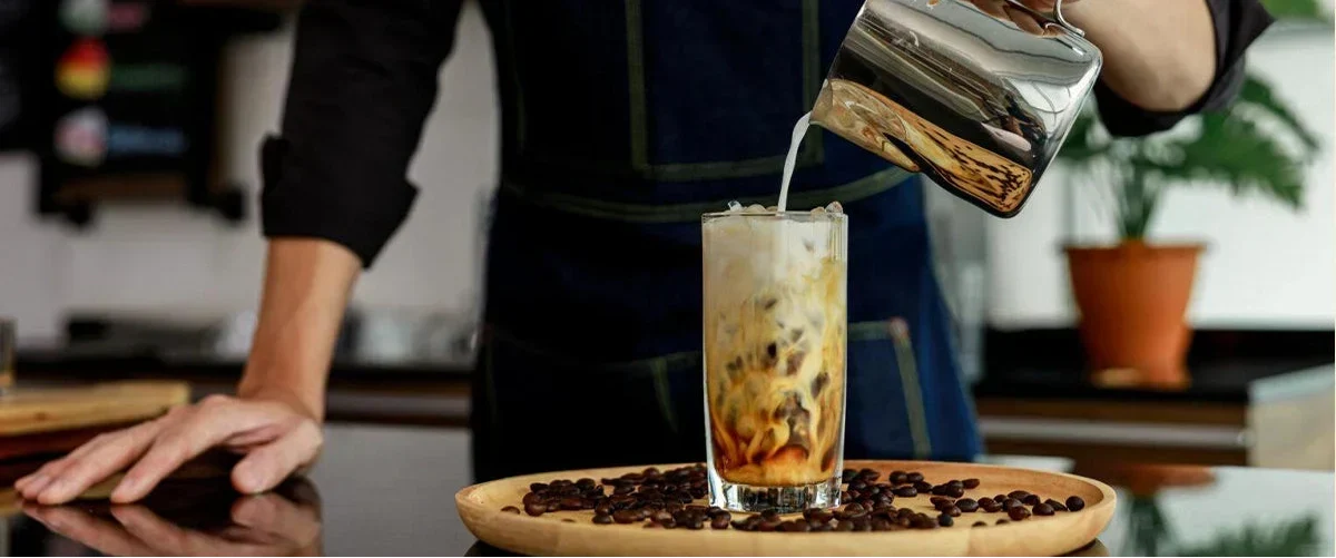 Barista gießt erfrischenden Eiskaffee ein – perfektes Sommerrezept.
