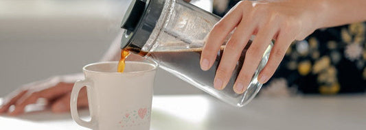 Hand gießt Kaffee auf 