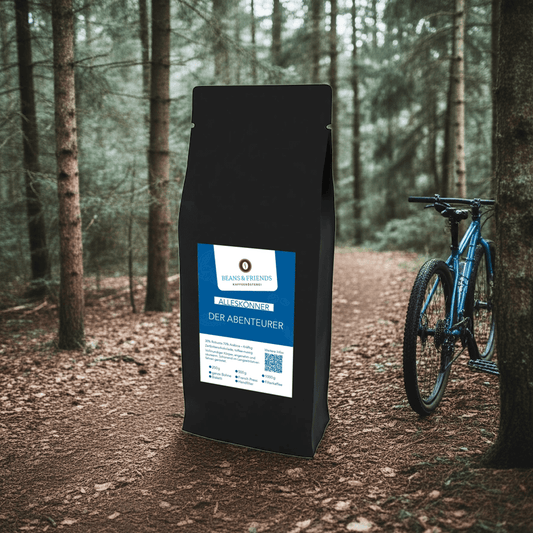 Die Kaffeesorte „Alleskönner Abenteurer“ inszeniert inmitten der Natur – im Hintergrund ein dichter Wald und ein blaues Mountainbike, das Abenteuerlust und Outdoor-Genuss verbindet.
