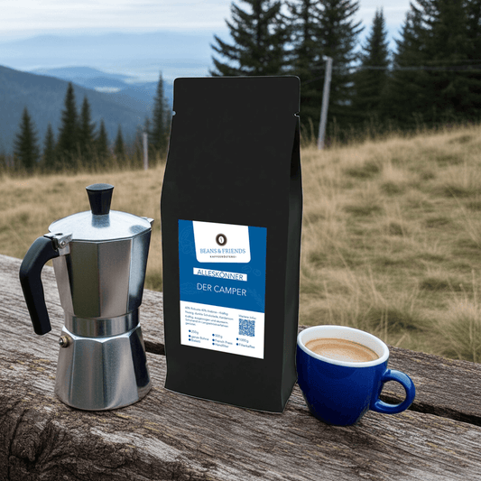 Die Kaffeesorte „Alleskönner“ inszeniert auf Waldboden mit grüner Wiese im Hintergrund – stilvoll ergänzt durch eine Bialetti-Espressokanne und eine Tasse cremiger Cappuccino.