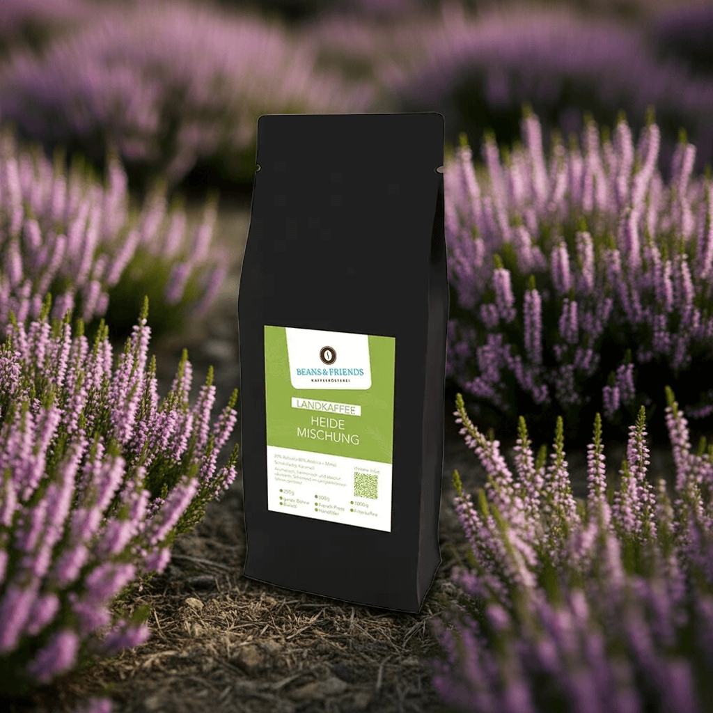Die Tüte „Heidekaffee“ steht vor einem Meer aus blühender Heide – ein harmonischer Kaffeemoment, inspiriert von der Schönheit der Natur.