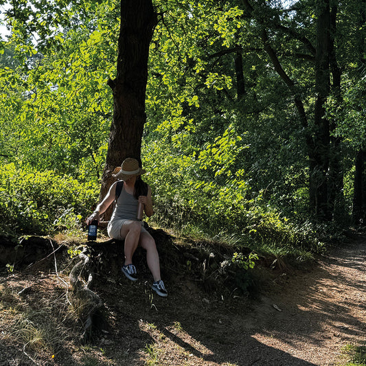 „Sandra macht eine kleine Pause auf einem Wanderweg, umgeben von schönem Grün. Mit einem Sonnenhut genießt sie die entspannte Atmosphäre und hat passend dazu den Wanderer, unseren leckeren Röstkaffee, dabei.“

