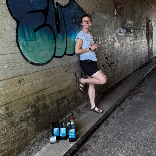 „Sandra in einer urbanen Umgebung, umgeben von Beton und von Jugendlichen bemalten Wänden, die durch ihre Kunst eine besondere Atmosphäre schaffen. Der kalte Beton strahlt plötzlich in einem neuen Licht. Hier präsentiert Sandra unsere Länderkaffees, das passende Blau ihres Outfits harmoniert perfekt mit der Sprühkunst an der Wand.“
