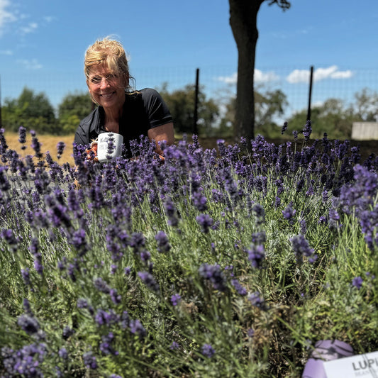„Tina mit einer Tasse Lavendelkaffee im Vordergrund, umgeben von einem blühenden Lavendelfeld. Sie genießt ihren Kaffee in dieser perfekten, duftenden Umgebung.“
