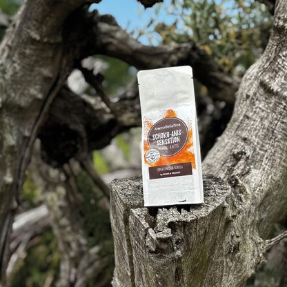 „Inmitten einer passenden Umgebung mit alten Olivenbäumen, die einen besonderen Reiz ausstrahlen, präsentieren wir den Gewürzkaffee Schoko-Anis auf einem abgebrochenen Baumstumpf. Es passt einfach alles zusammen – Natur, Ruhe und der verführerische Geschmack.“
