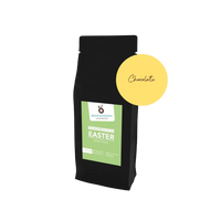 Easter Coffee Chocolate – Edle schwarze Verpackung mit frühlingshaftem grünen Etikett und runder  gelber Aufkleber, der die Geschmacksrichtung der Sorte anzeigt. 